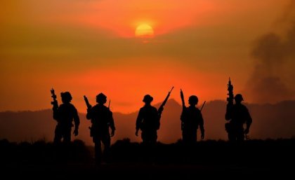 The US is funding melanoma research expecting a rise in cases among soldiers. Image: Adobe A group of soldiers with weapons silhouetted against a smoky red sky